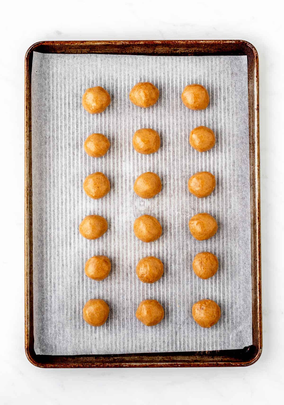 No bake peanut butter balls without powdered sugar lined up a baking sheet.