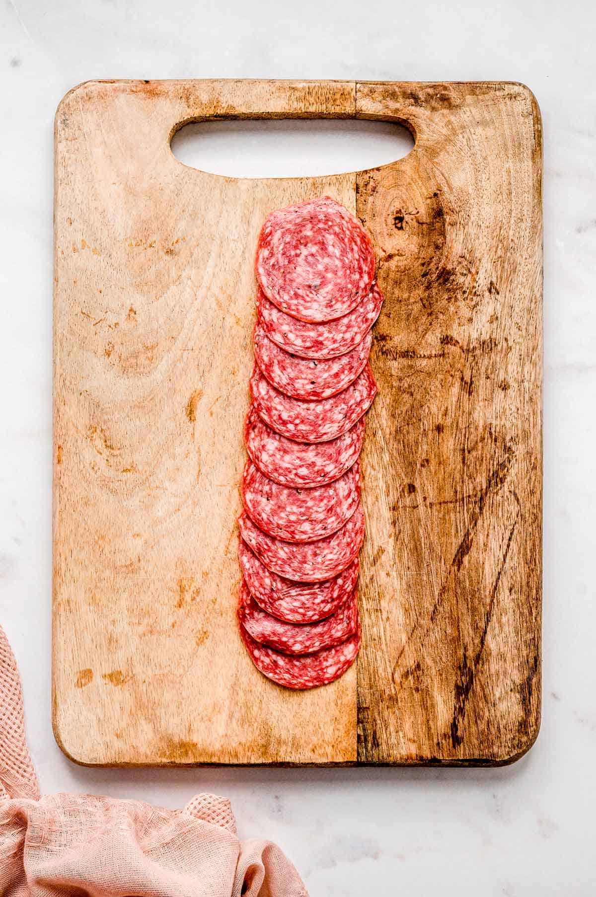 Salami slices on a wooden cutting board.