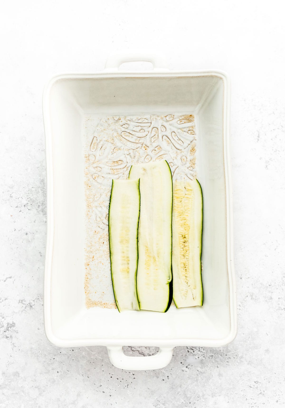 Strips of zucchini on the bottom of a casserole dish.
