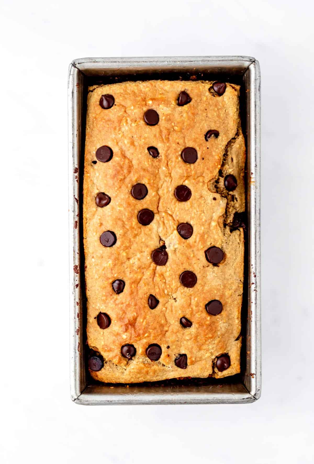 Baked protein banana bread in a loaf pan with chocolate chips.