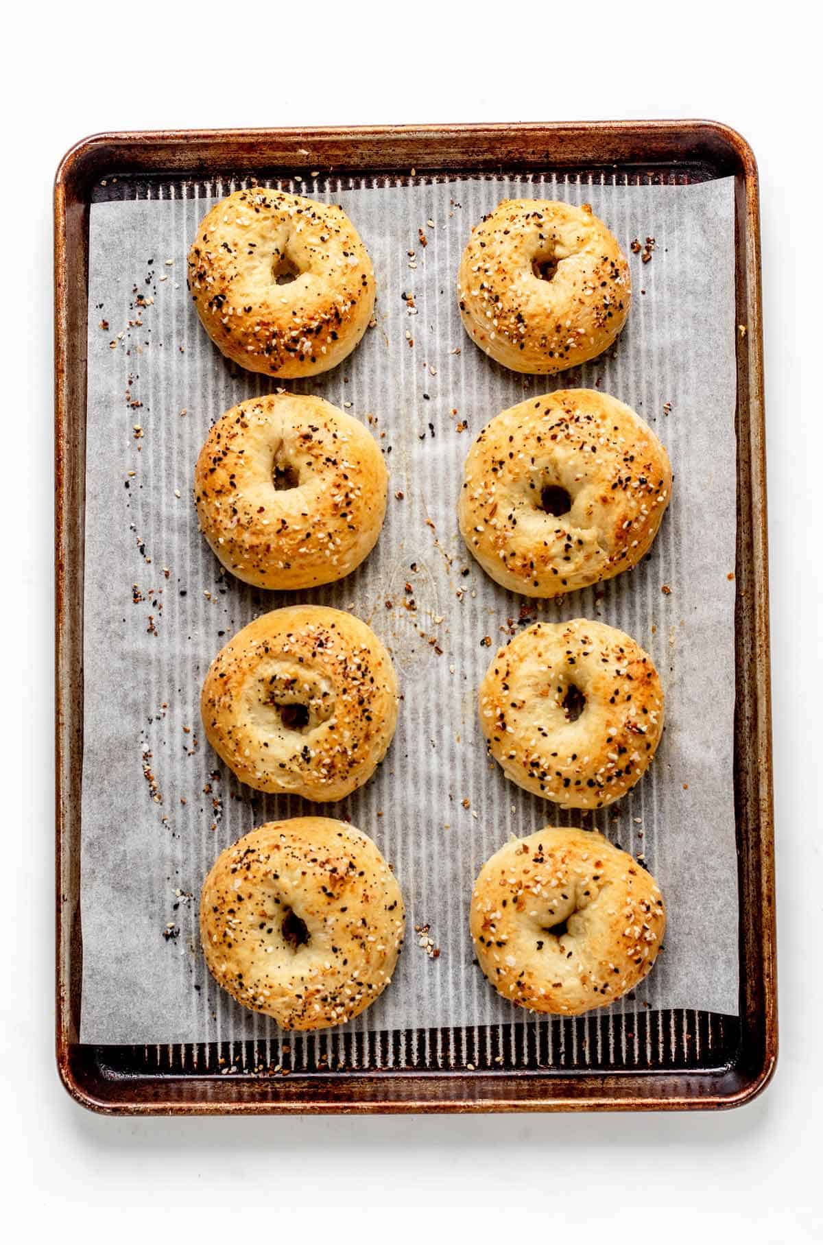 Bagels on a parchment paper lined baking sheet after cooking in the oven.