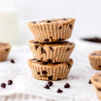A stack of three protein cookie dough bites with chocolate chips scattered around them.