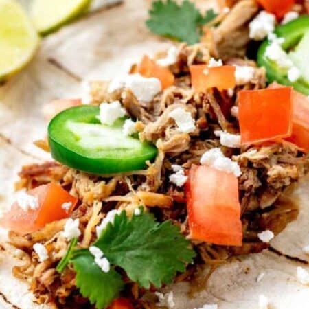 Close up image of leftover pulled pork carnitas on a tortilla with toppings.
