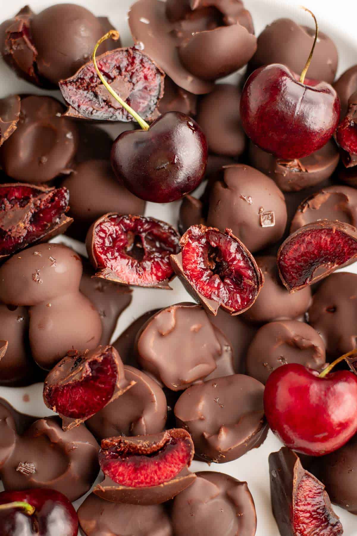 A close-up of chocolate covered cherries on a white plate.