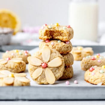 A stack of four lemon almond flour cookies with one leaning up against the stack.