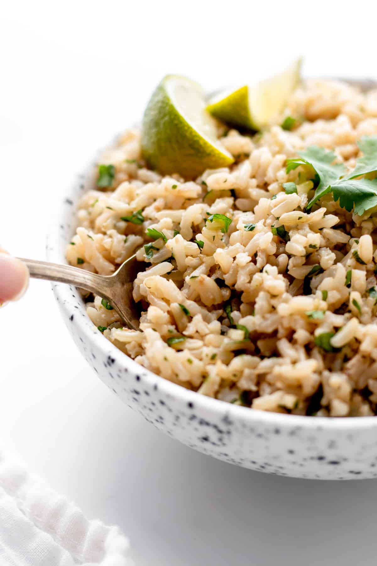 A close-up of one half of a bowl of coconut cilantro lime rice, with a fork in it.