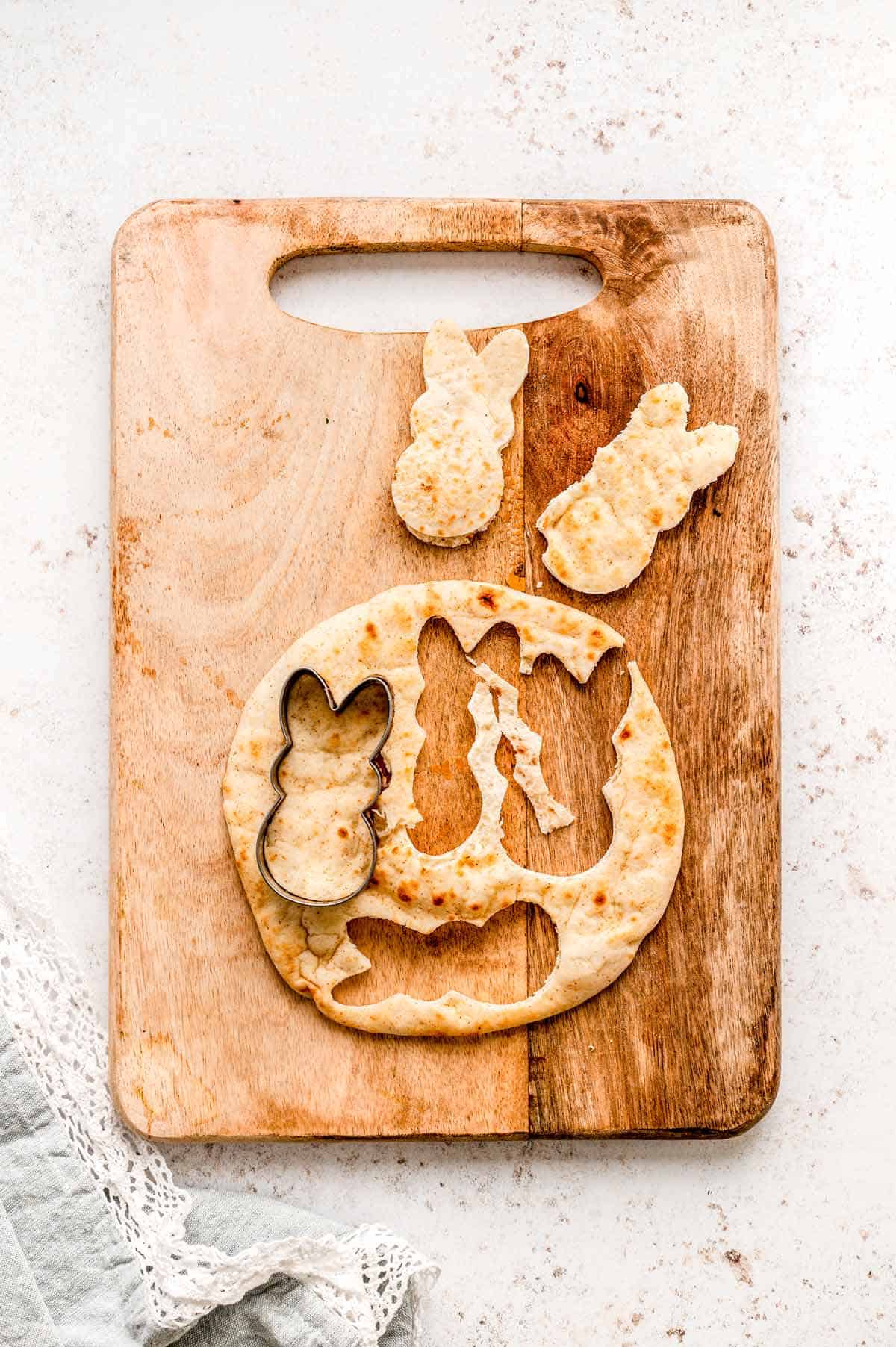Cutting bunny shapes out of pita bread using a cookie cutter.