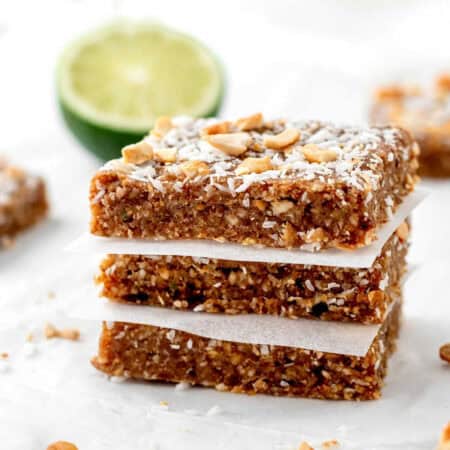 A stack of three key lime protein bars topped with coconut and chopped cashews.