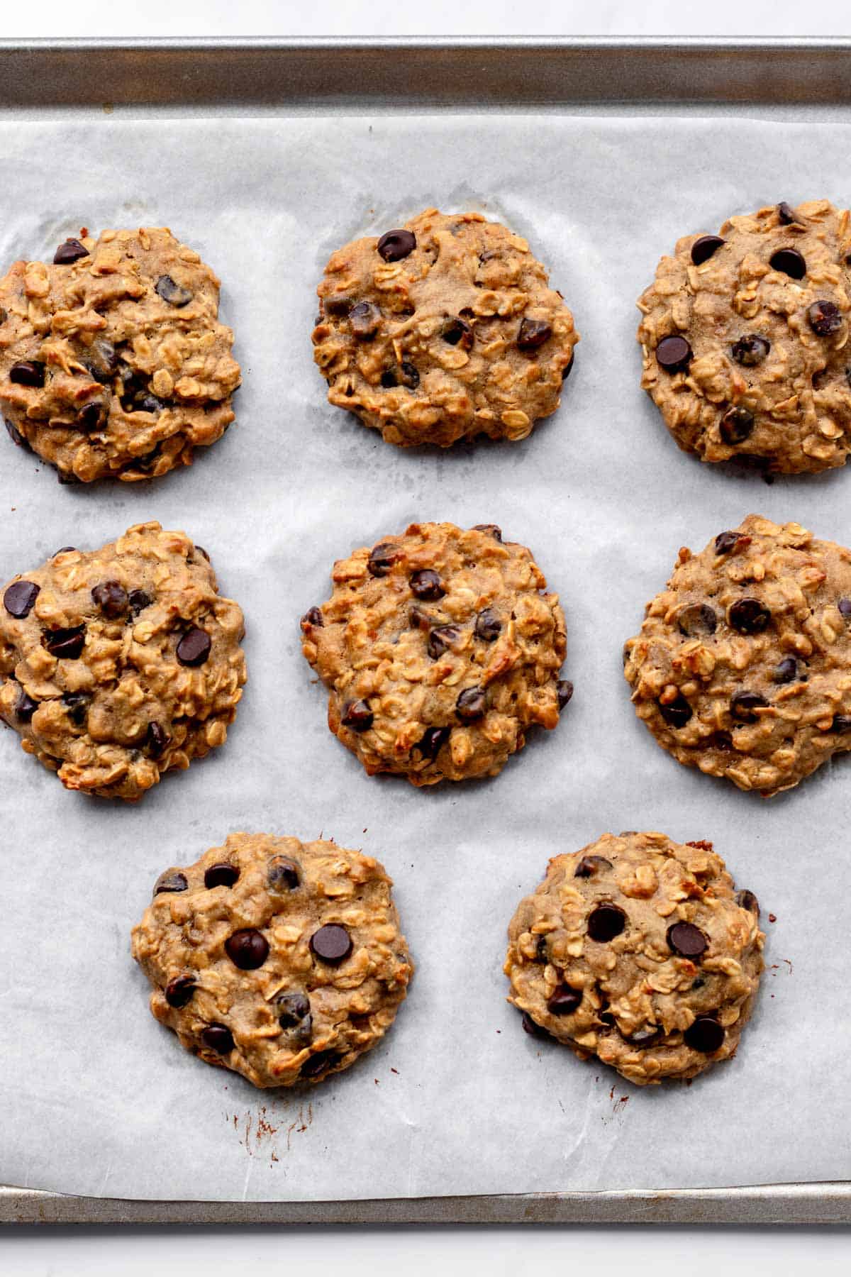 Bird's eye view of baked banana protein cookies on a baking sheet.