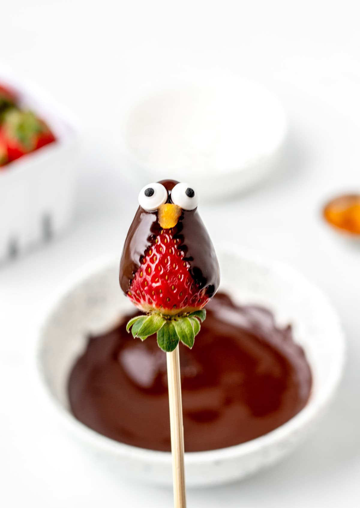 Penguin eyes and beak added to the melted chocolate on a strawberry.