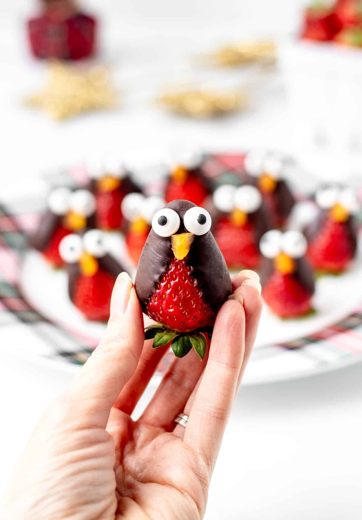 A hand holding up a strawberry penguin