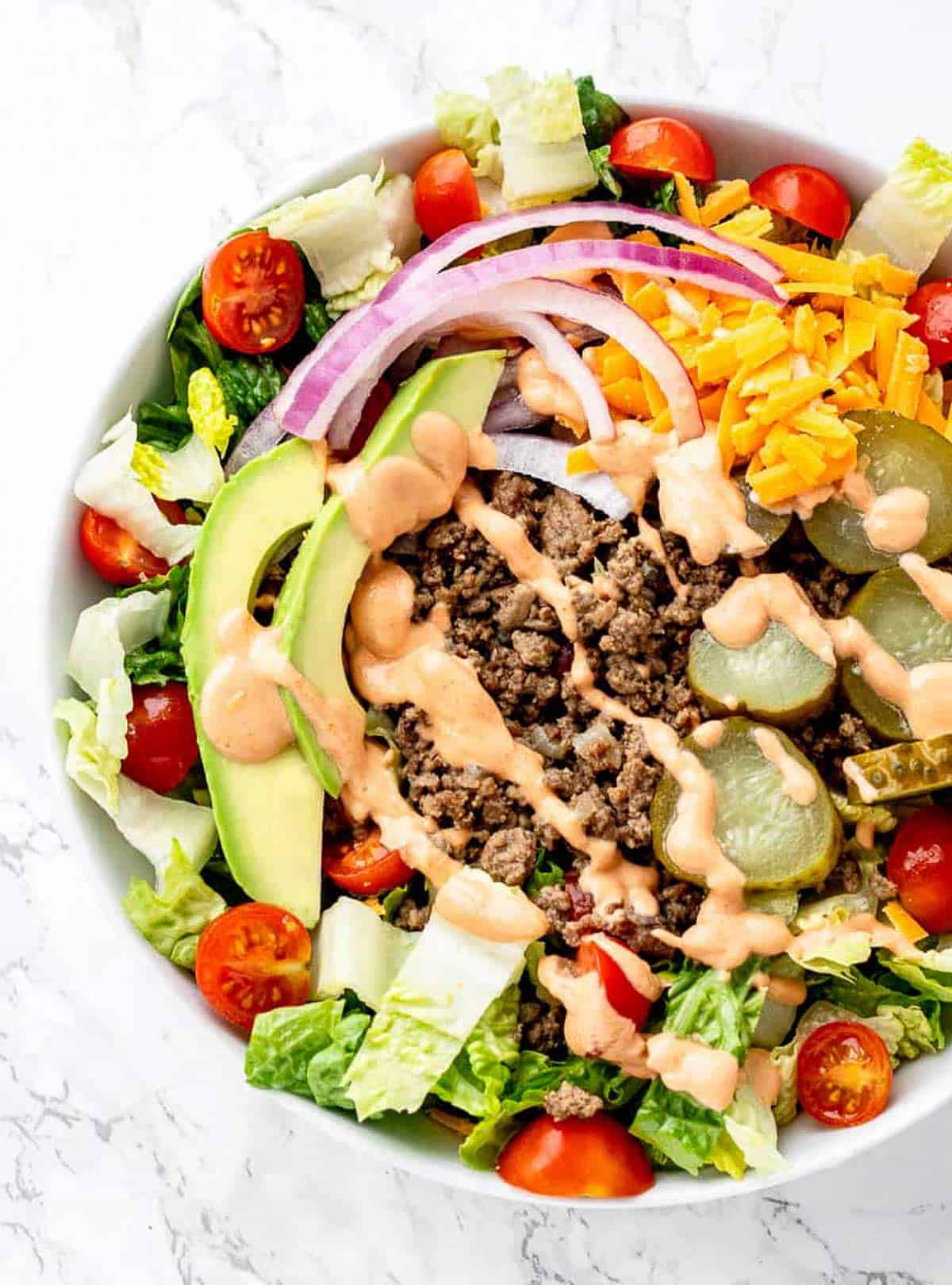 Bird's eye view of a healthy burger salad served in a large white bowl.