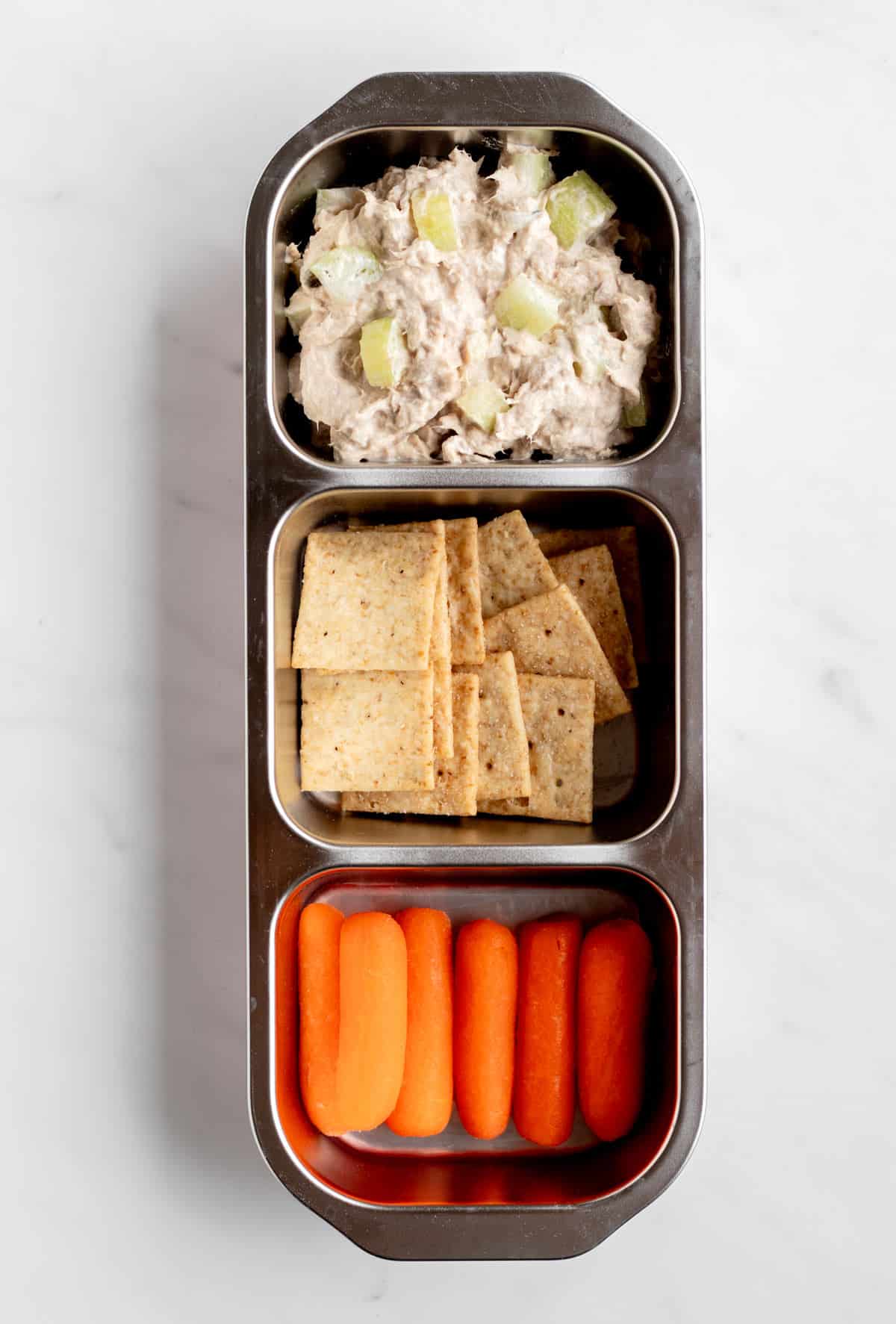 Tuna salad with almond flour crackers, and baby carrots in a snack box.