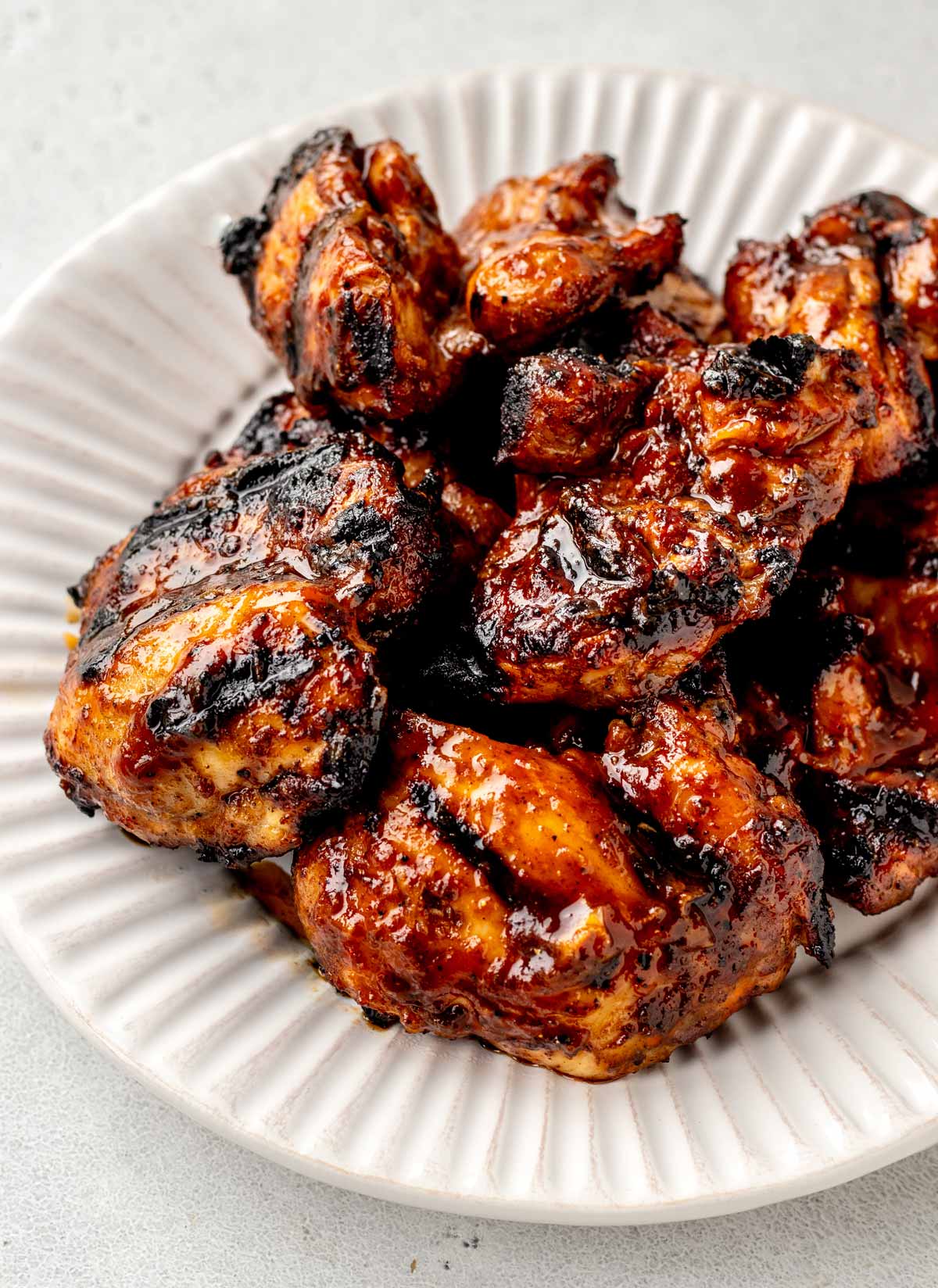 A plate of bbq grilled skinless boneless chicken thighs.
