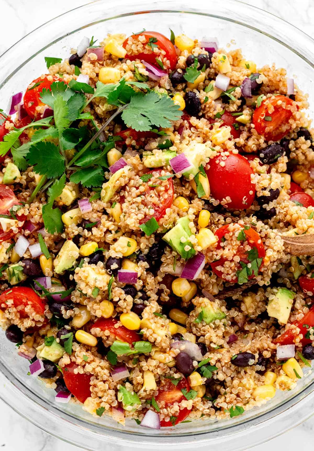 Bird's eye view of a spoon in a bowl of Mexican quinoa salad.