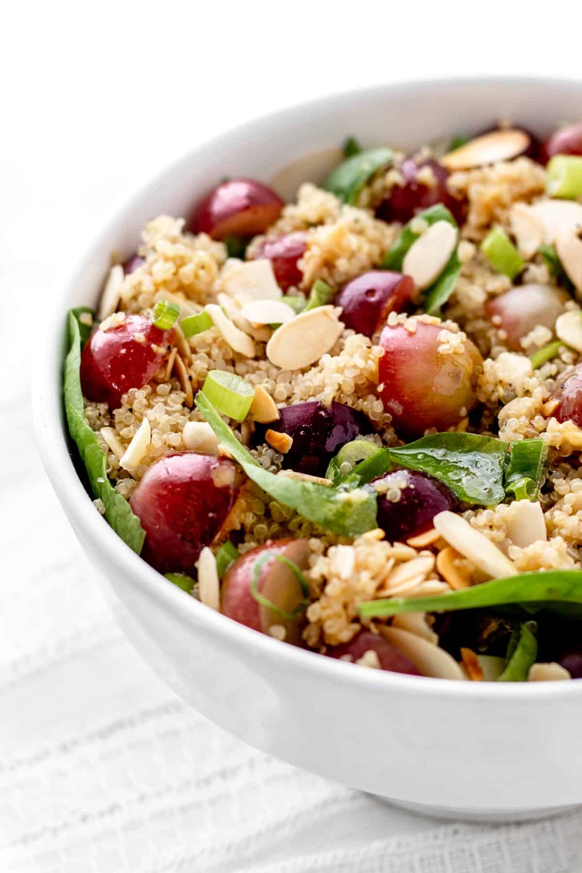 Up close image of grape quinoa salad with spinach and slice almonds.