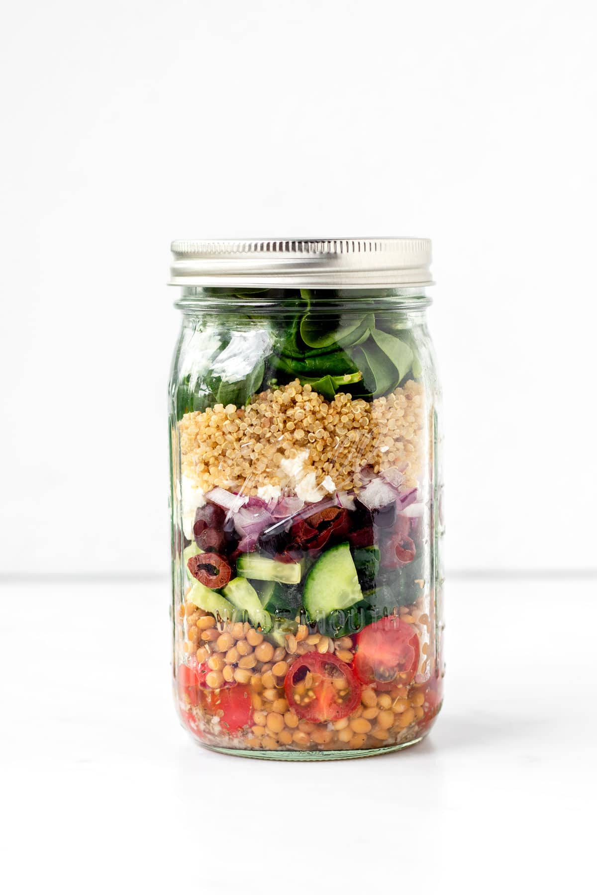 Mason jar quinoa salad against a white background.