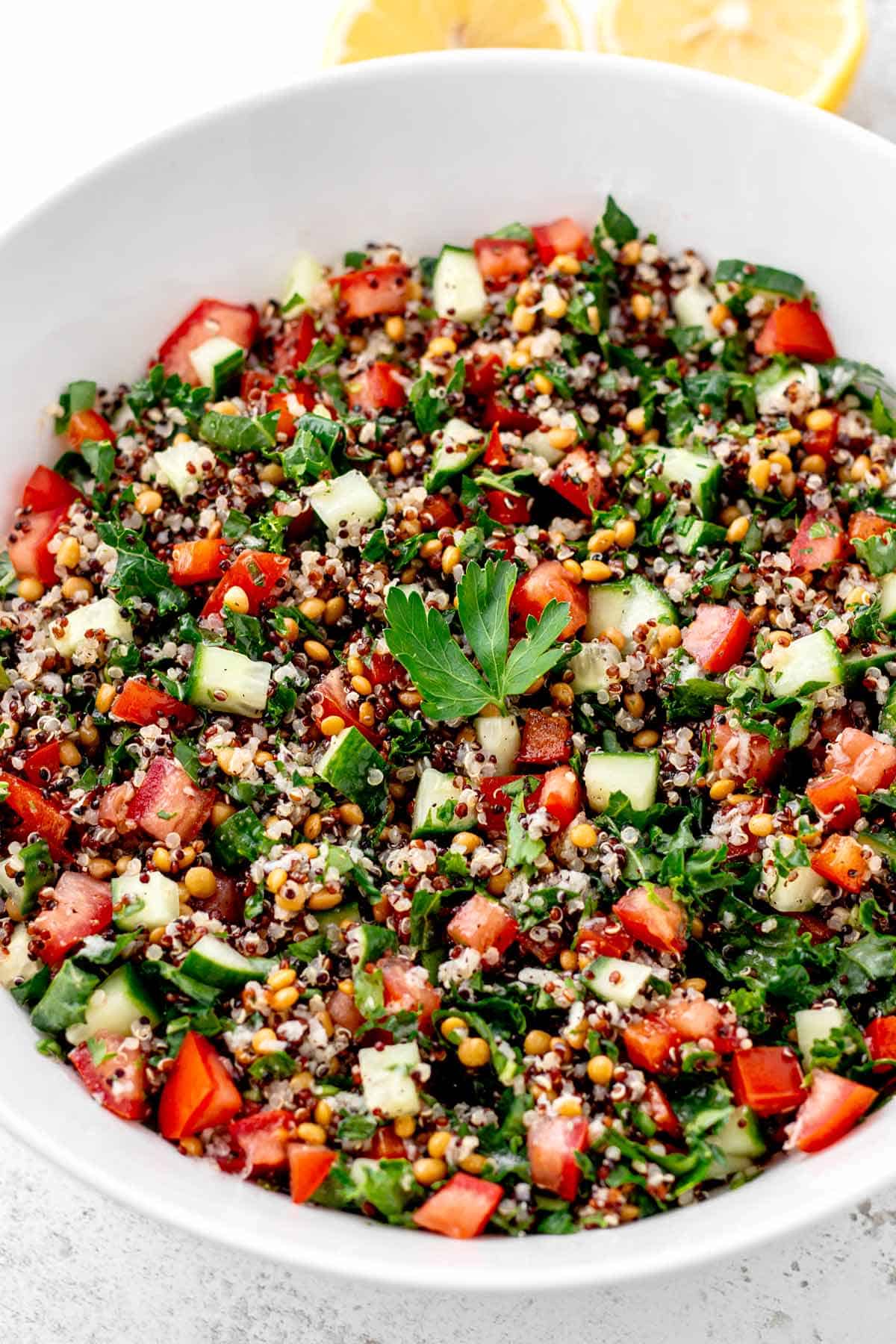 A large bowl of copycat Costco quinoa salad next to some lemons.