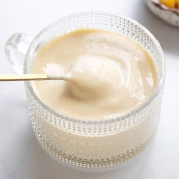 Close up image of a spoon scooping up some protein mango dole whip out of a glass cup.