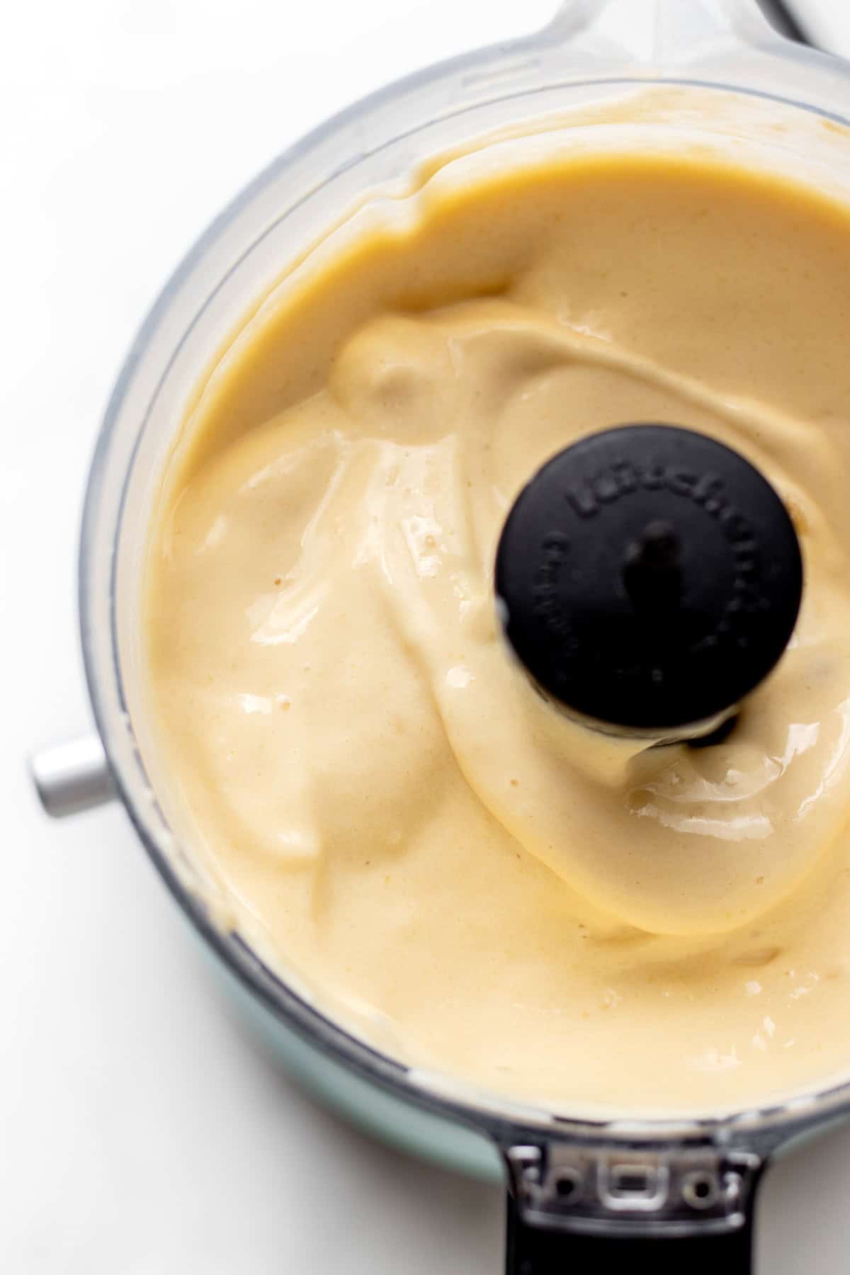 Bird's eye view of creamy frozen mango whip in a mini food processor.