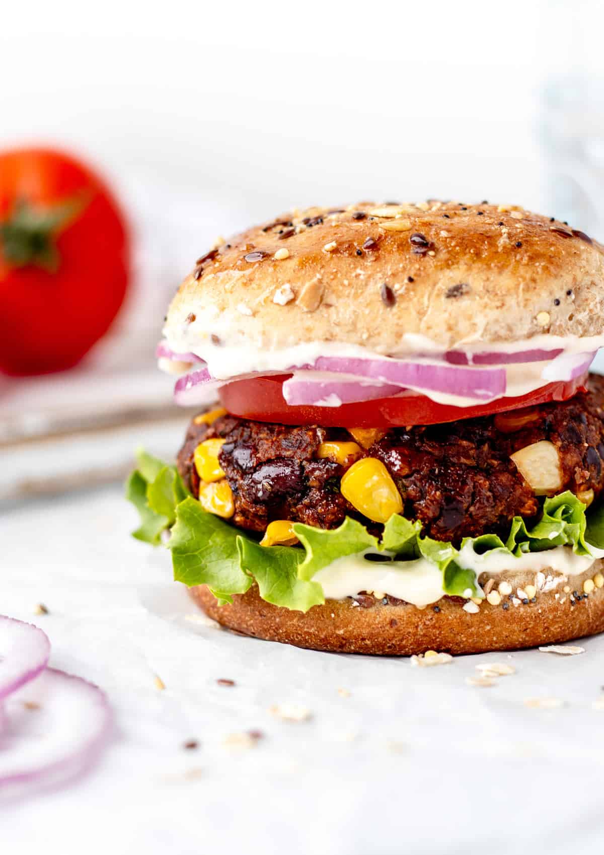 A close up of a spicy bean burger on a bun with toppings.