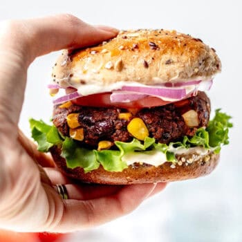 A hand holding a spicy black bean burger with oats.