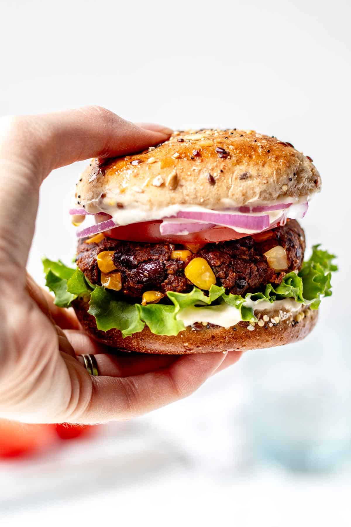 A hand holding a vegan spicy black bean burger.
