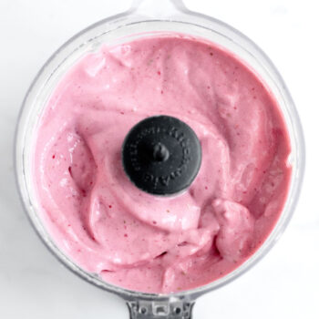 Up close bird's eye view of blended frozen strawberry cottage cheese dessert in a mini food processor.