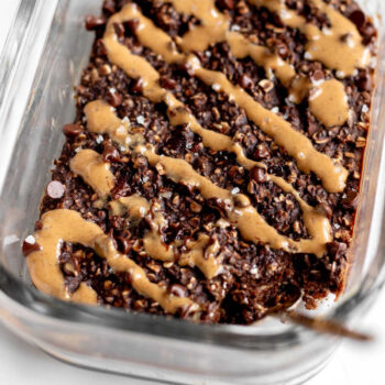 Chocolate protein baked oats in a glass meal prep container with a spoon.