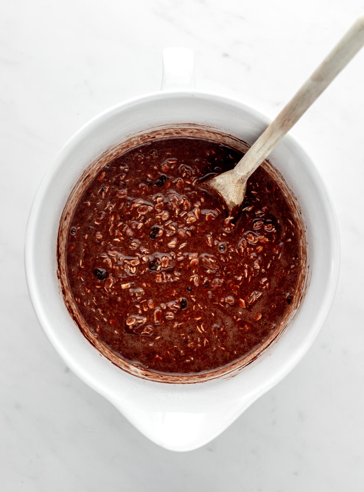 Batter for the chocolate baked oats in a large bowl with a mixing spoon.