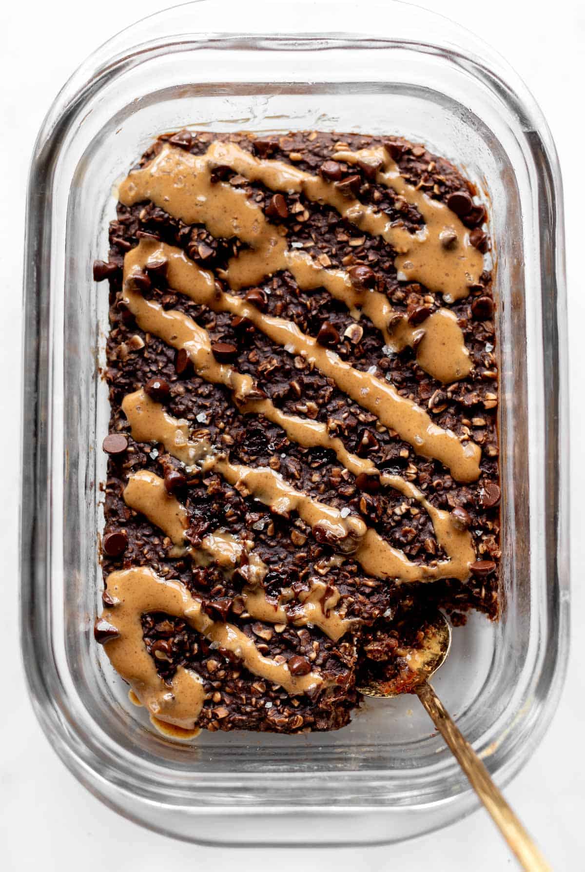 Bird's eye view of a glass container with protein chocolate baked oats drizzled with peanut butter.